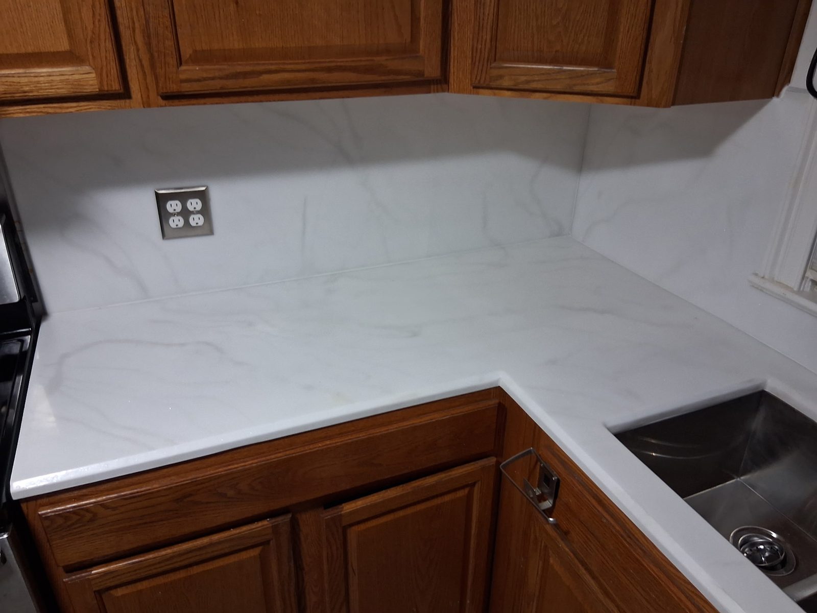Installed white kitchen counter and matching backsplash.