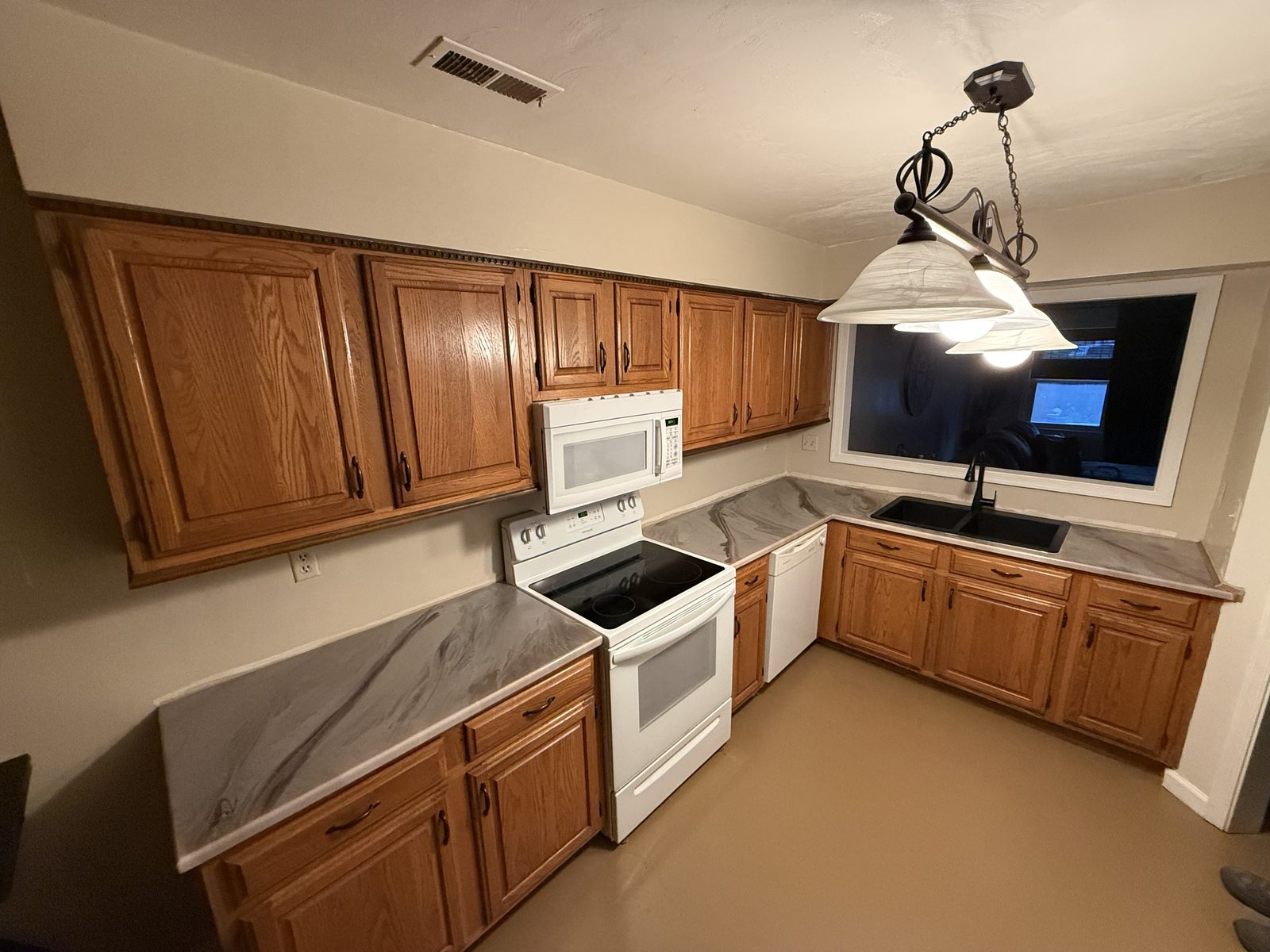 Installed kitchen counters with wood cabinetry and a black sink.