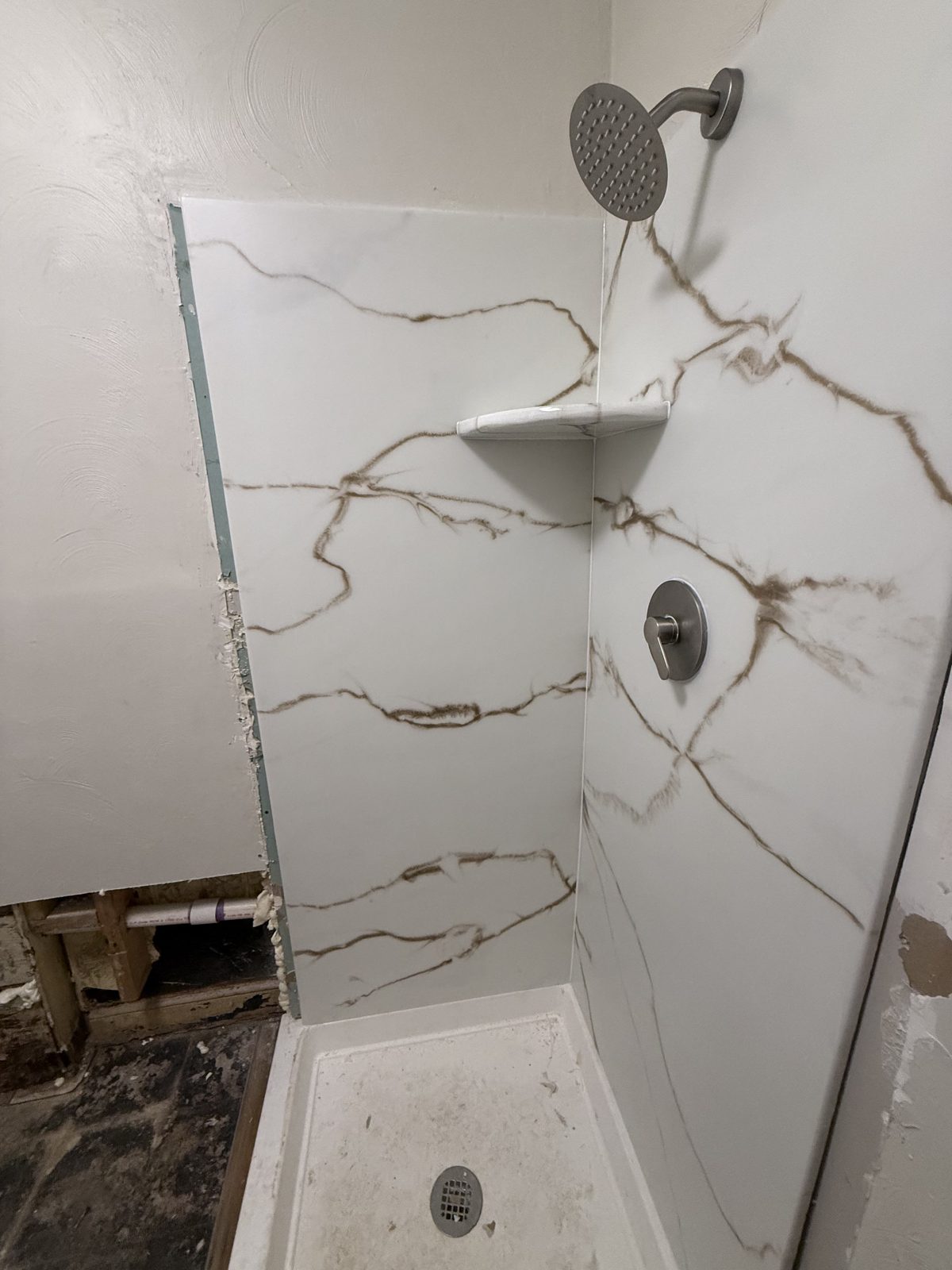 Installation in progress: white-and-gold shower walls before the doors were fitted.
